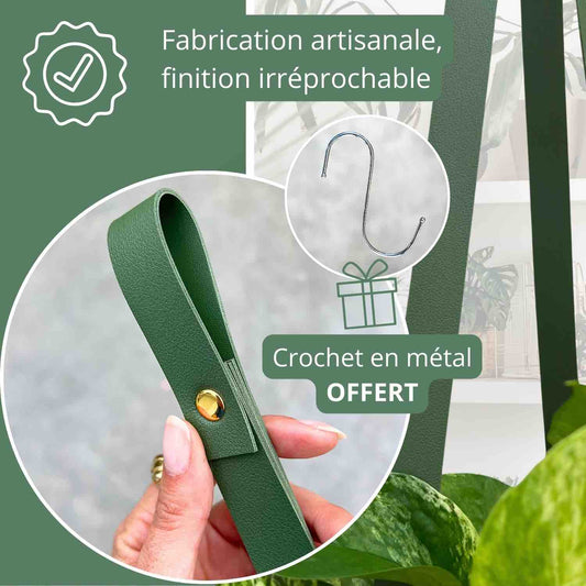 Une suspension pour plantes en similicuir vert foncé avec un bouton doré et un crochet en métal argenté