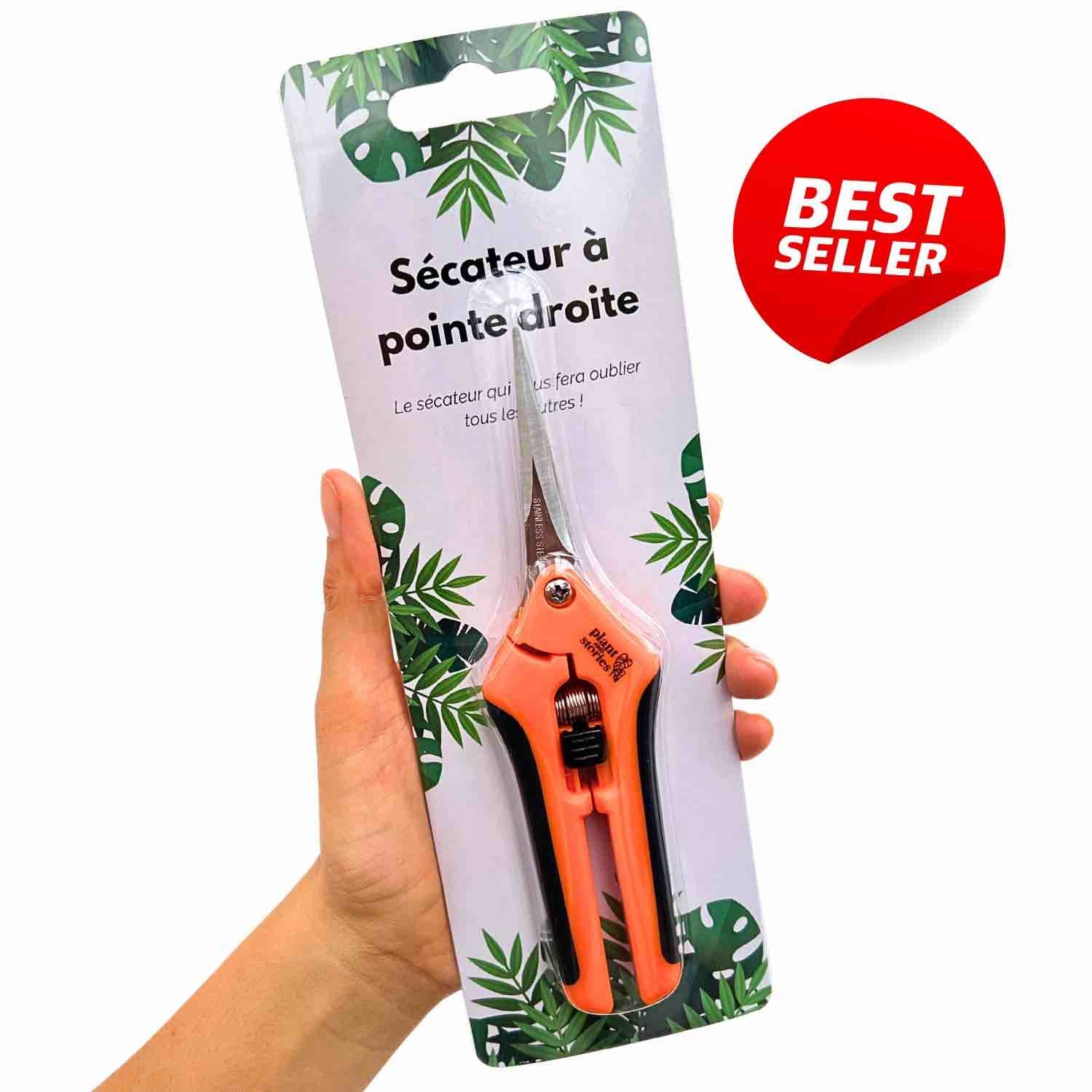 Un sécateur pour plante à pointe droite avec des poignées orange et noires dans son emballage à motifs de feuilles