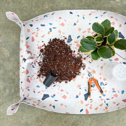 Grand tapis de rempotage en simili cuir blanc à motifs terrazzo colorés avec terreau, plante et outils