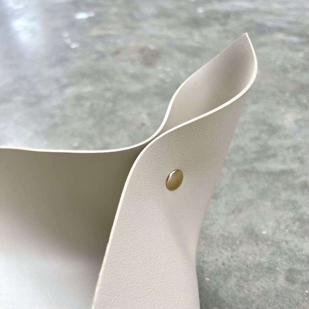 Un gros plan sur un tapis de rempotage en simili cuir beige clair avec des boutons pression en laiton doré