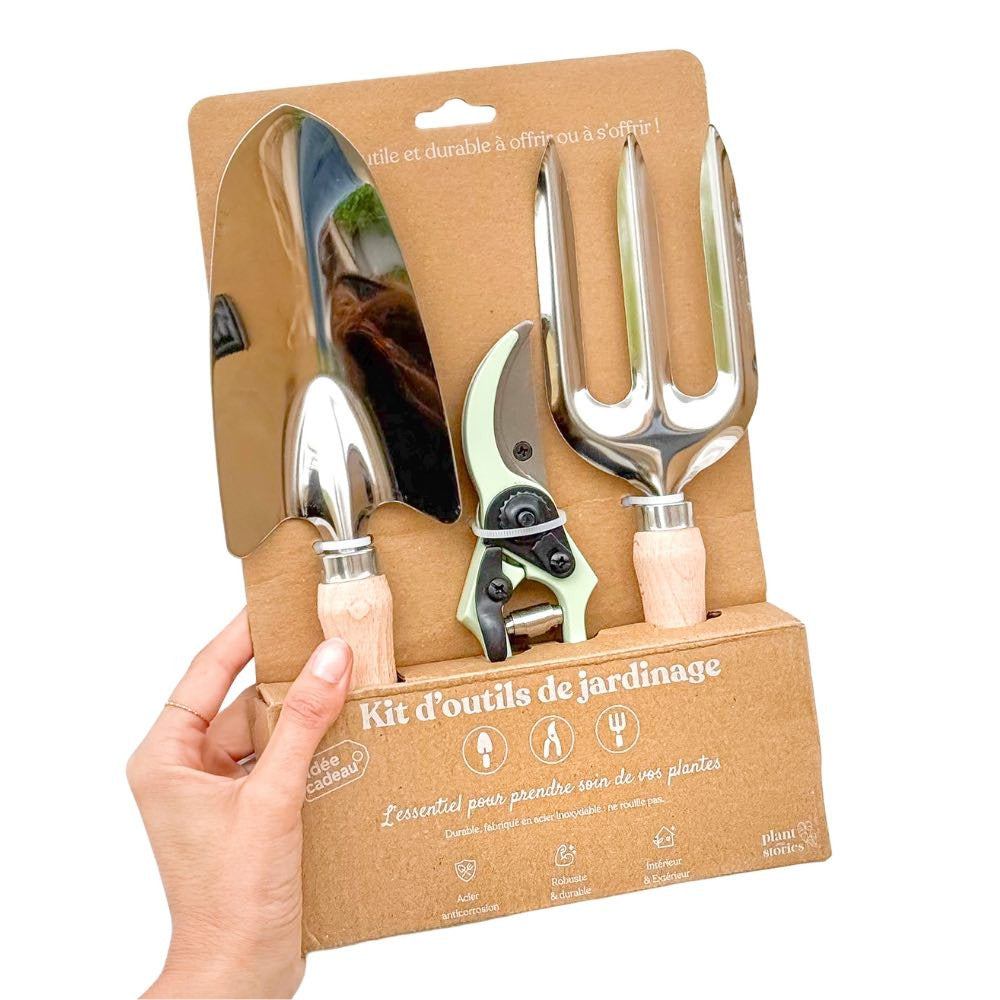 Un kit d'outils de jardinage avec une petite pelle, un sécateur vert menthe et une fourche, sur fond blanc