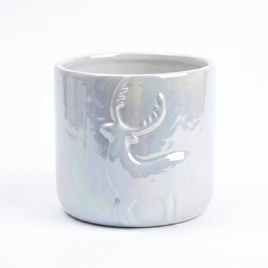 Un des cache-pots céramique de Noël avec un motif renne en relief et une finition irisée, sur fond blanc